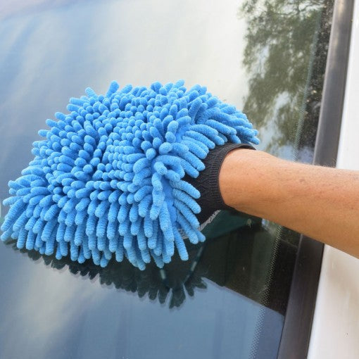 Person cleaning a car window with a blue microfiber cloth