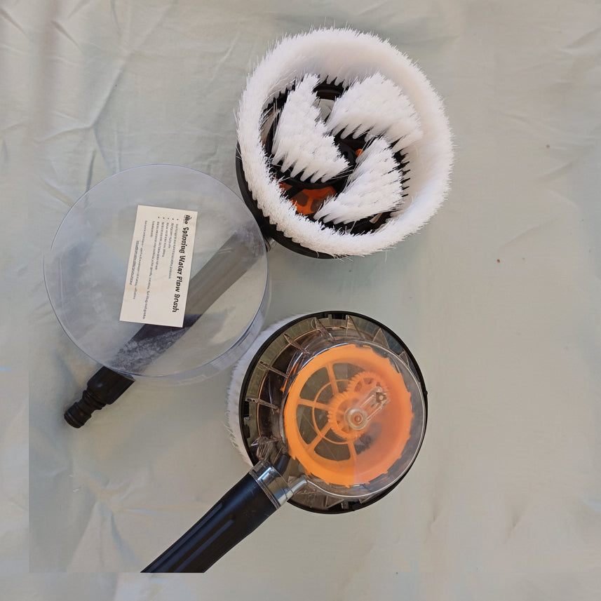 Cleaning brush with black and white bristles and orange center, on a light gray background.