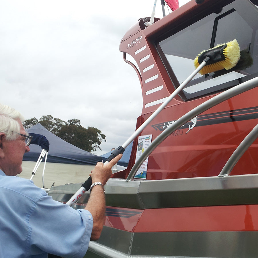 Person cleaning a boat with a Filko Cleaning brush on a cloudy day