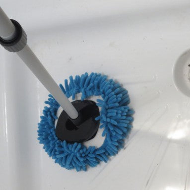 Cleaning tool with blue bristle head being used to clean a drain.