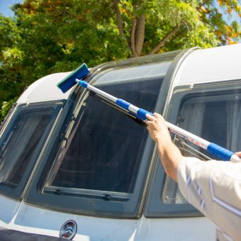 Person cleaning the windows of a camper van with a squeegee.